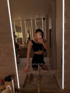 Person taking a mirror selfie in a bathroom with a lit mirror.